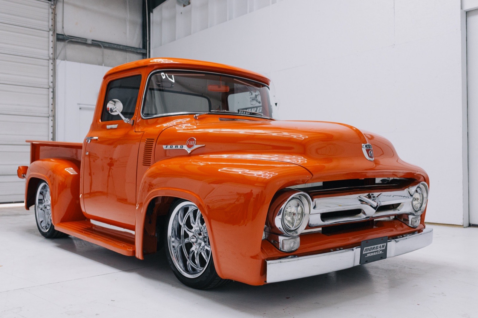 1956 Ford F-100 stepside in vibrant orange — front three-quarter view, restored by Morgan Muscle Cars