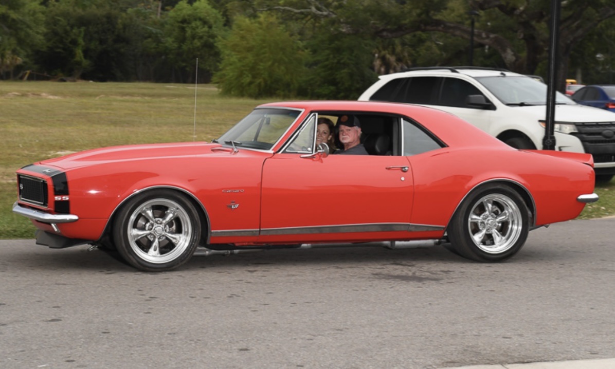 Couple cruising in an orange 1967 Chevrolet Camaro RS/SS resto-mod built by Morgan Muscle Cars in Pelham, Alabama.