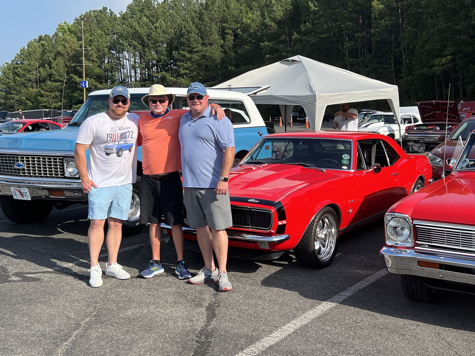 The Morgan family beside a red Chevrolet Camaro at a classic car show — family-owned muscle car shop in Pelham, Alabama.